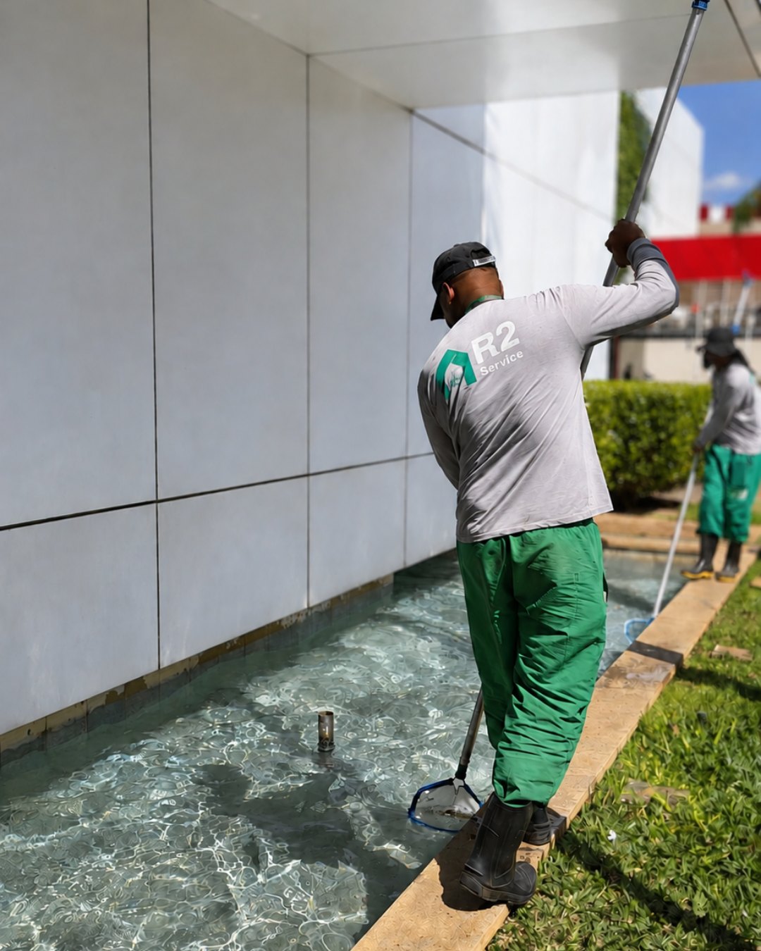 Profissional uniformizado da R2 Service limpando espelho d'água com peneira